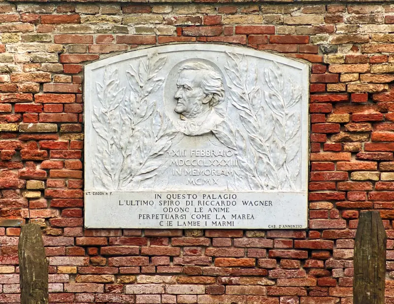 A carved marble memorial plaque to Richard Wagner set into the stone wall of Palazzo Vendramin Calergi, its Italian inscription weathered and streaked.